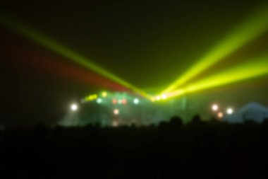 Sahne ışıkları olan, bulanık fotoğraflı konser kalabalığının siluetleri.
