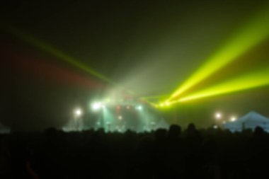 Sahne ışıkları olan, bulanık fotoğraflı konser kalabalığının siluetleri.