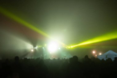 Sahne ışıkları olan, bulanık fotoğraflı konser kalabalığının siluetleri.