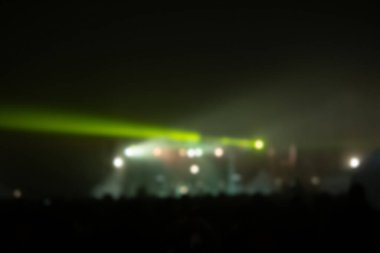 Sahne ışıkları olan, bulanık fotoğraflı konser kalabalığının siluetleri.