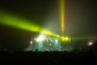 Sahne ışıkları olan, bulanık fotoğraflı konser kalabalığının siluetleri.