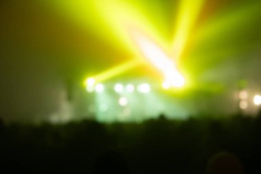 Sahne ışıkları olan, bulanık fotoğraflı konser kalabalığının siluetleri.