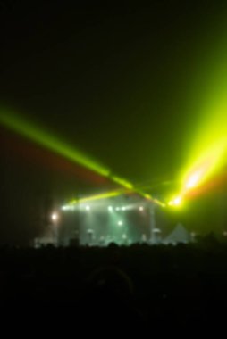 Sahne ışıkları olan, bulanık fotoğraflı konser kalabalığının siluetleri.