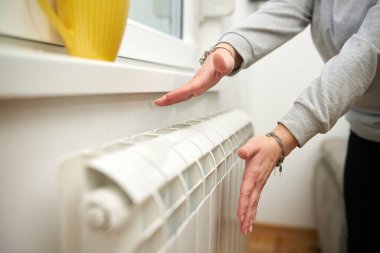 Soğuk bir kış gününde ısınan kadın, enerji ve gaz krizi, soğuk oda, ısıtma sorunları.