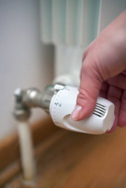 Soğuk bir kış gününde ısıtma valfini değiştiren kadın, enerji ve gaz krizi, soğuk oda, ısıtma sorunları.