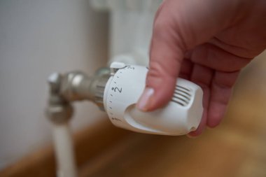 Soğuk bir kış gününde ısıtma valfini değiştiren kadın, enerji ve gaz krizi, soğuk oda, ısıtma sorunları.