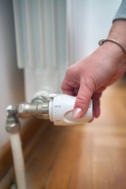 Soğuk bir kış gününde ısıtma valfini değiştiren kadın, enerji ve gaz krizi, soğuk oda, ısıtma sorunları.