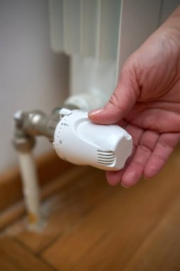 Soğuk bir kış gününde ısıtma valfini değiştiren kadın, enerji ve gaz krizi, soğuk oda, ısıtma sorunları.