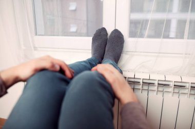 Soğuk bir kış gününde evin ısıtıcı kaloriferinde çoraplı bir adamın ayakları..