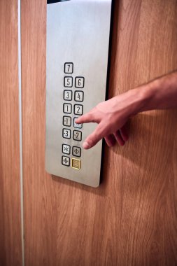 Binadaki asansör düğmelerine basan kişi.