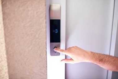 Binadaki asansör düğmelerine basan kişi.