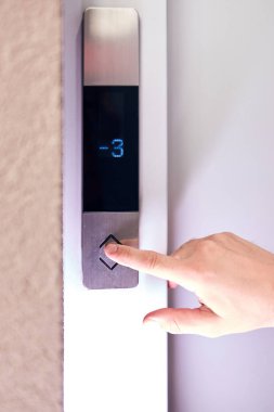 Binadaki asansör düğmelerine basan kişi.