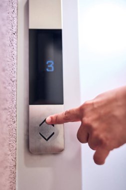 Binadaki asansör düğmelerine basan kişi.