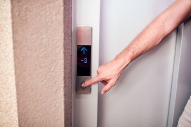 Binadaki asansör düğmelerine basan kişi.