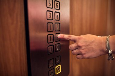 Binadaki asansör düğmelerine basan kişi.