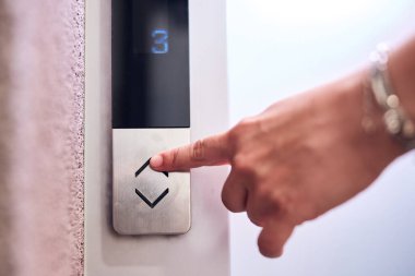 Binadaki asansör düğmelerine basan kişi.