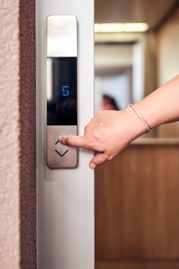 Binadaki asansör düğmelerine basan kişi.