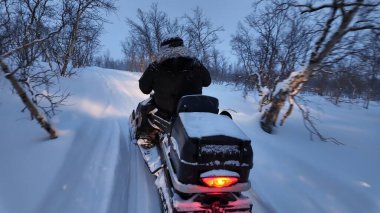 Kışın kırsal kesimde kar arabası kullanan insanlar.