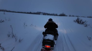 Kışın kırsal kesimde kar arabası kullanan insanlar.