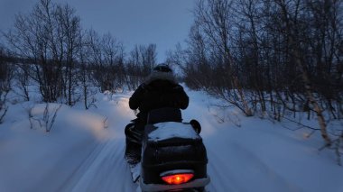 Kışın kırsal kesimde kar arabası kullanan insanlar.