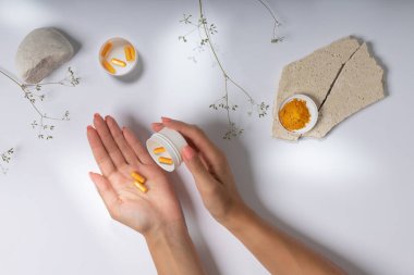 Güzel bir arka planda hapları ya da vitaminleri tutan ellerin fotoğrafı.