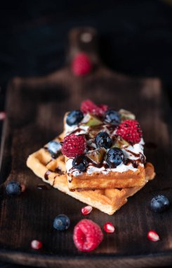 Krem şantili lezzetli waffle ve güzel bir arka planda taze meyve.