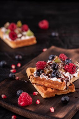 Krem şantili lezzetli waffle ve güzel bir arka planda taze meyve.