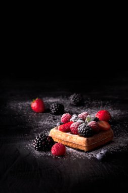 Ahududu, böğürtlen ve diğer taze meyvelerle nefis waffle, güzel koyu arkaplanda şekerleme serpiştirme