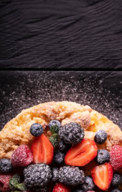 Tatlı kek ya da çilekli turta ve diğer taze meyveler güzel bir arka planda pudra şekeri serpiştirilmiş.