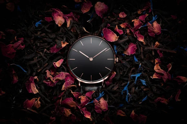 A beautiful ladies watch with a black dial and a gold frame on a beautiful floral background