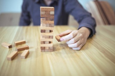 Ellerin tahta blok kule oyunu oynadığı iş stratejisi kavramı risk ve istikrarı sembolize ediyor. Risk yönetimi planlanıyor.