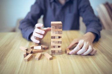 Ellerin tahta blok kule oyunu oynadığı iş stratejisi kavramı risk ve istikrarı sembolize ediyor. Risk yönetimi planlanıyor.