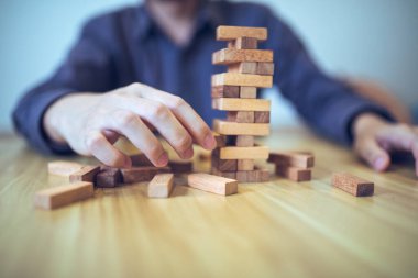 Ellerin tahta blok kule oyunu oynadığı iş stratejisi kavramı risk ve istikrarı sembolize ediyor. Risk yönetimi planlanıyor.
