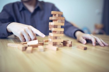 Ellerin tahta blok kule oyunu oynadığı iş stratejisi kavramı risk ve istikrarı sembolize ediyor. Risk yönetimi planlanıyor.