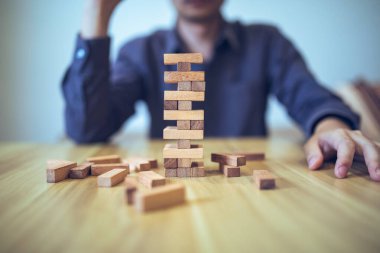 Ellerin tahta blok kule oyunu oynadığı iş stratejisi kavramı risk ve istikrarı sembolize ediyor. Risk yönetimi planlanıyor.