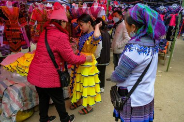 Can Cau, Vietnam - 17 Aralık 2022: Lao Cai, Vietnam 'daki Can Cau pazarında geleneksel bir elbise deneyen bir kadın.