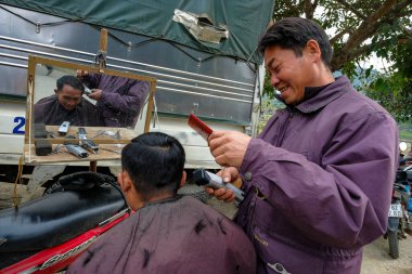 Bac Ha, Vietnam - 18 Aralık 2022: Bir berber Vietnam 'daki Bac Ha pazarında bir müşterinin saçını kesiyor.