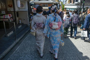 Kyoto, Japonya - 28 Mart 2023: Kimono giymiş kadınlar Japonya 'nın Kyoto kentindeki kaldırımlı yaya sokağı Sannenzaka' da yürüyorlar.