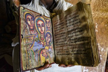 Hawzen, Ethiopia - January 9, 2018: A priest showing an old Bible in the Abuna Yemata Guh church in Hawzen, Tigray, Ethiopia clipart