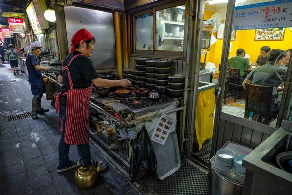 stock image Seoul, South Korea - July 6, 2023: A woman preparing food at the Namdaemun Market in Seoul, is the oldest market in South Korea.