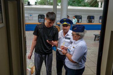 Zhetygen, Kazakistan - 8 Ağustos 2023: Kazakistan 'daki Zhetygen tren istasyonundaki bir yolcuya bilgi veren tren müfettişleri.