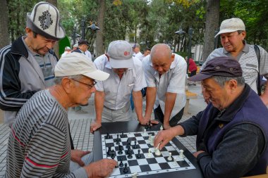 Bişkek, Kırgızistan - 4 Eylül 2023: Kırgızistan 'ın Bişkek kentindeki bir parkta satranç oynayan insanlar.