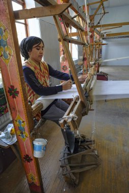Margilan, Özbekistan - 20 Ekim 2023: Margilan, Özbekistan 'da ipekle dokuma tezgahında çalışan bir kadın.