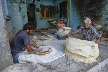 Ahmedabad, Hindistan - 11 Ocak 2024: Hindistan 'ın eski Ahmedabad kasabasında papad, ince kabuklu ekmek yapan erkekler.