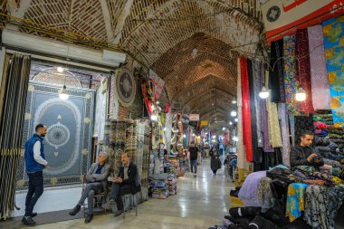 Urmia, Iran - April 20, 2024: Men selling carpets and fabrics in the Urmia Historical Bazaar, Iran. clipart