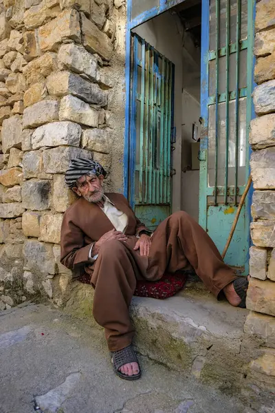 Uraman Takht, İran - 15 Nisan 2024: İran 'ın Kürdistan kentinde Uraman Takht' ta bir sokakta oturan bir adamın portresi.