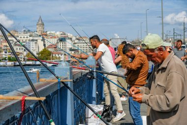İstanbul, Türkiye - 20 Eylül 2024: İstanbul, Türkiye 'de Galata Köprüsü' nde arka planda Galata Kulesi ile balık tutan insanlar.