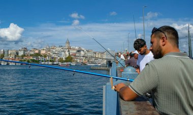 İstanbul, Türkiye - 20 Eylül 2024: İstanbul, Türkiye 'de Galata Köprüsü' nde arka planda Galata Kulesi ile balık tutan insanlar.
