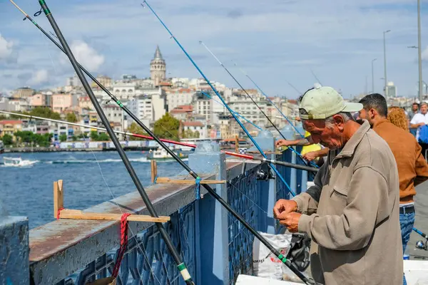 İstanbul, Türkiye - 20 Eylül 2024: İstanbul, Türkiye 'de Galata Köprüsü' nde arka planda Galata Kulesi ile balık tutan insanlar.