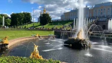 Saint-Petersburg - 4 Ekim 2022, Petergof. Güneşli bir günde Peterhof 'un alt parkında bronz heykeller ve bir sürü turist taşıyan Büyük Saray.